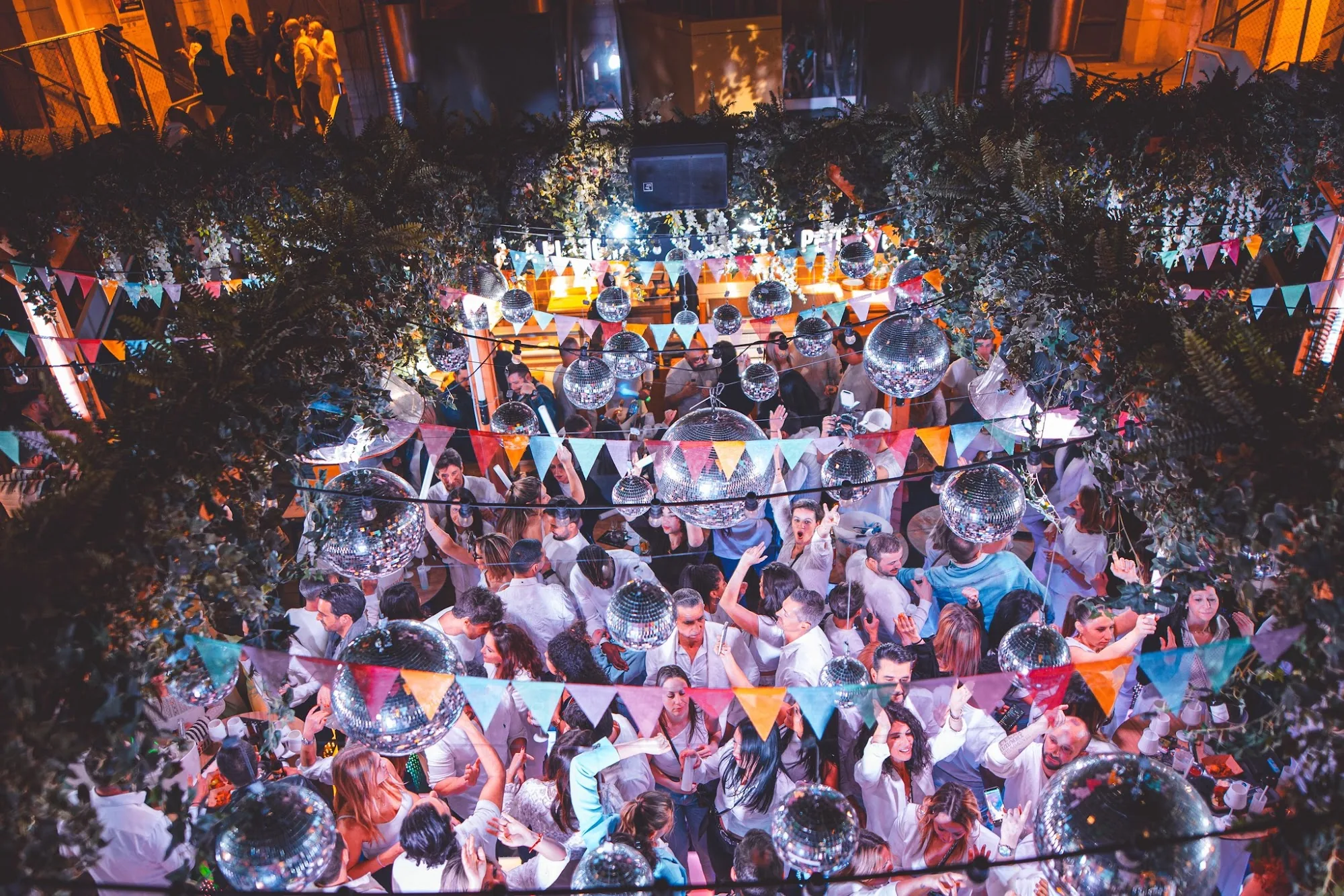 Aerial view of a packed dance floor with disco balls and a crowd at La Place des Canailles