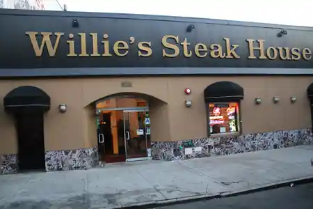 Willie's Steak House full storefront entrance with gold signage and neon window display, Bronx New York — salsa, bachata venue in New York