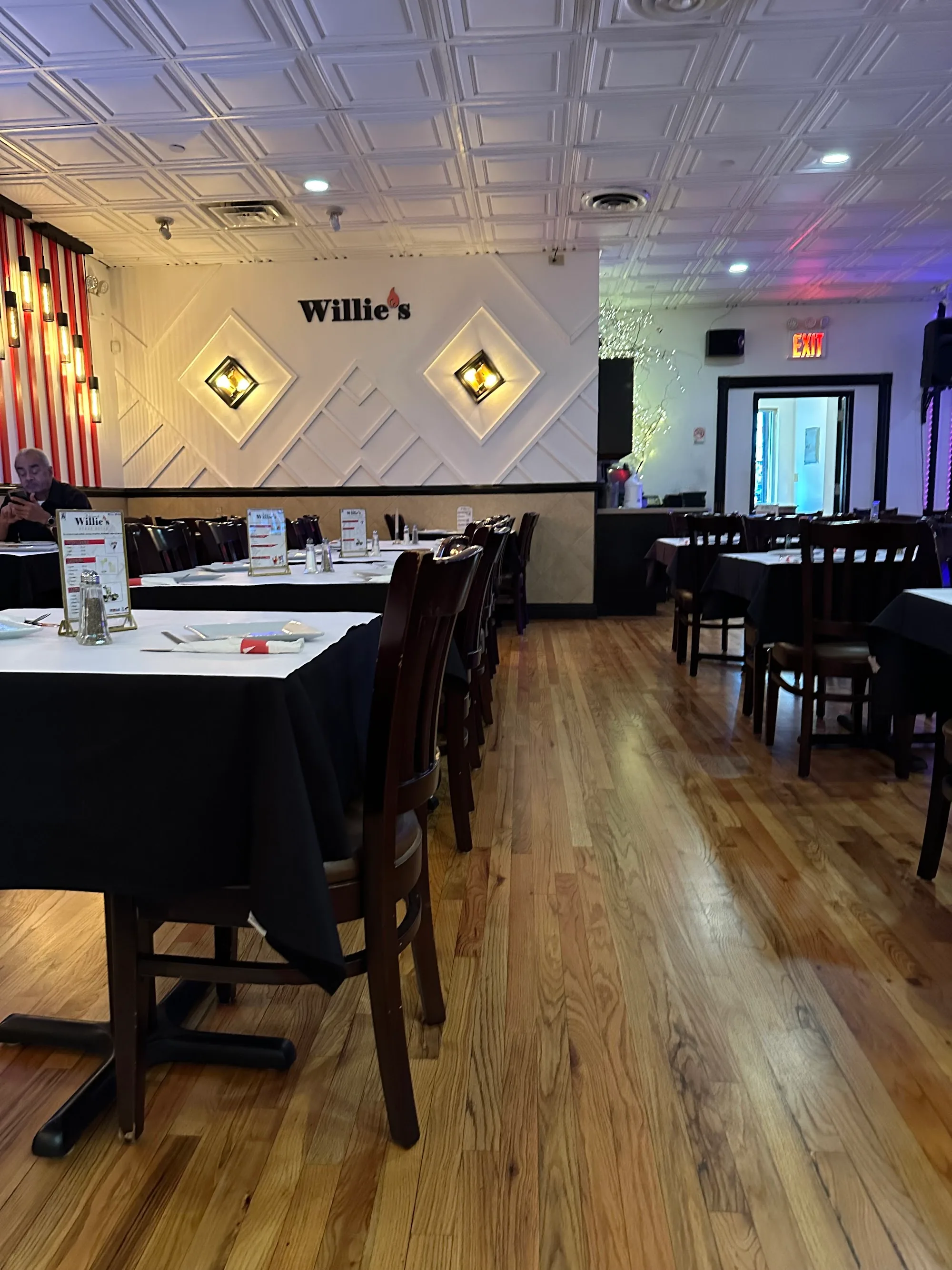 Interior dining room at Willie's Steak House Bronx with wooden floor and branded wall, Latin night venue