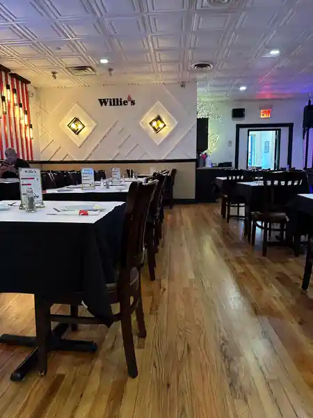 Interior dining room at Willie's Steak House Bronx with wooden floor and branded wall, Latin night venue — salsa, bachata venue in New York