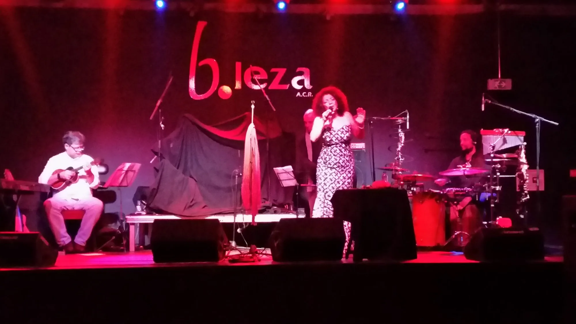 B.Leza live singer and band on stage under red lights with b.leza logo