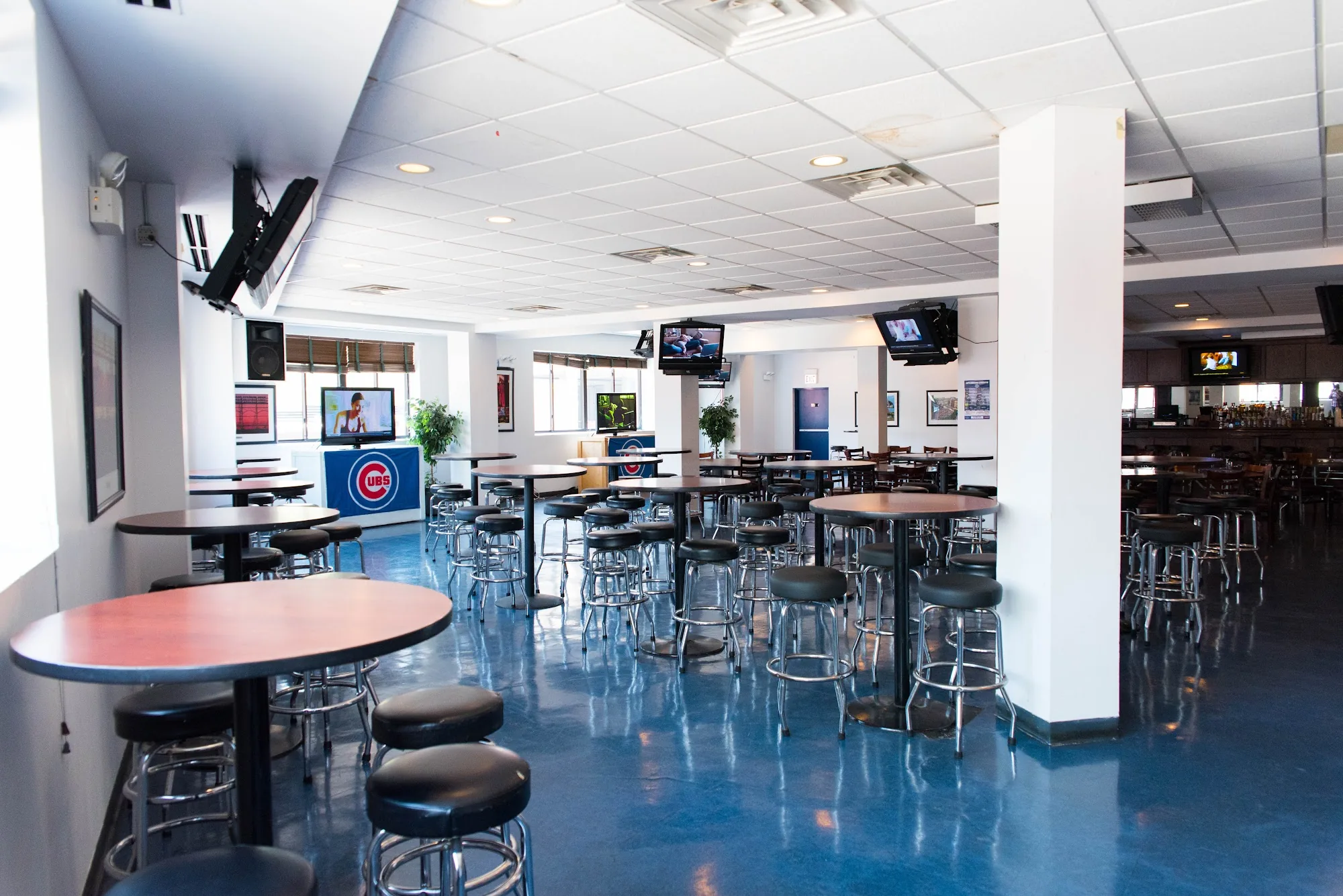 Interior of The Cubby Bear in Chicago with high-top tables, bar stools and a Chicago Cubs flag on the blue floor