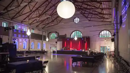 Spacious dance hall interior at Kedelhallen in Copenhagen with high industrial ceiling, stage, and wooden dance floor — salsa, bachata venue in Copenhagen