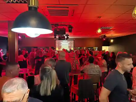Dance and party event at L'After with people on an illuminated dance floor, red stage lighting and projection screen — salsa, bachata, kizomba venue in Meylan