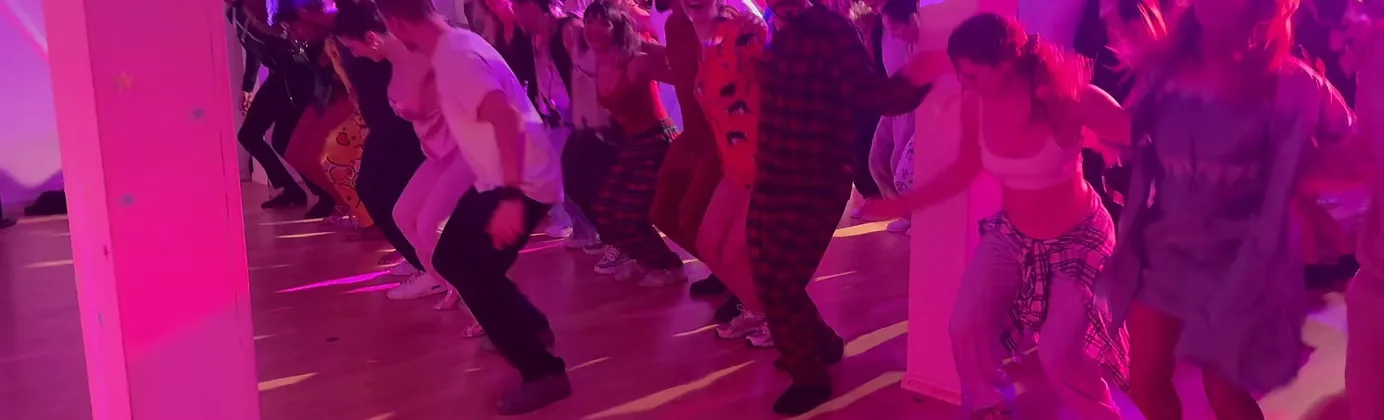 Crowd dancing on the wooden dance floor under pink lights at Bachata Basel in Basel