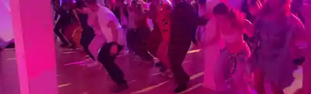 Crowd dancing on the wooden dance floor under pink lights at Bachata Basel in Basel