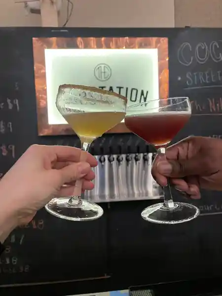 Cocktails toasted in front of the illuminated Substation bar sign in Boston — salsa venue in Boston
