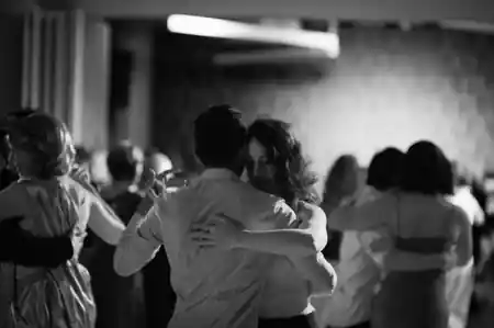 Couples enjoying social dancing at You Should Be Dancing in New York, captured in an atmospheric black and white photograph showing multiple pairs on the dance floor — salsa, bachata venue in New York