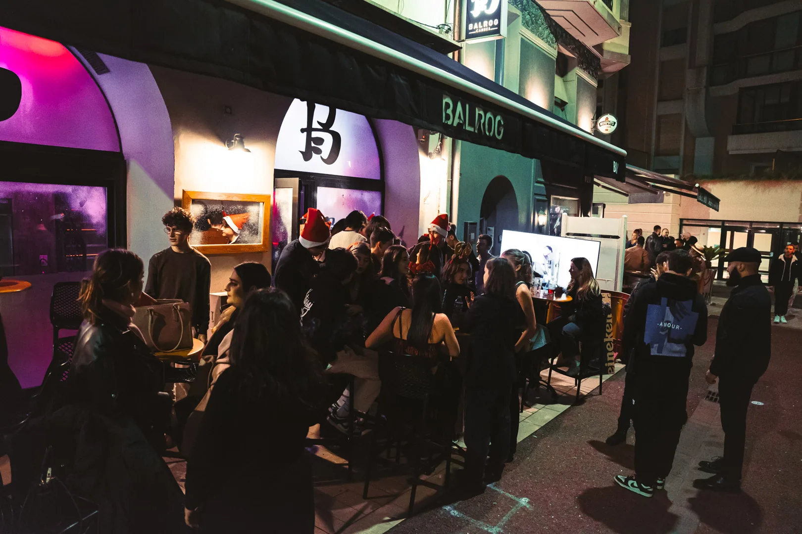 Exterior of Balrog Bar with crowd at night and branded signage, Cannes