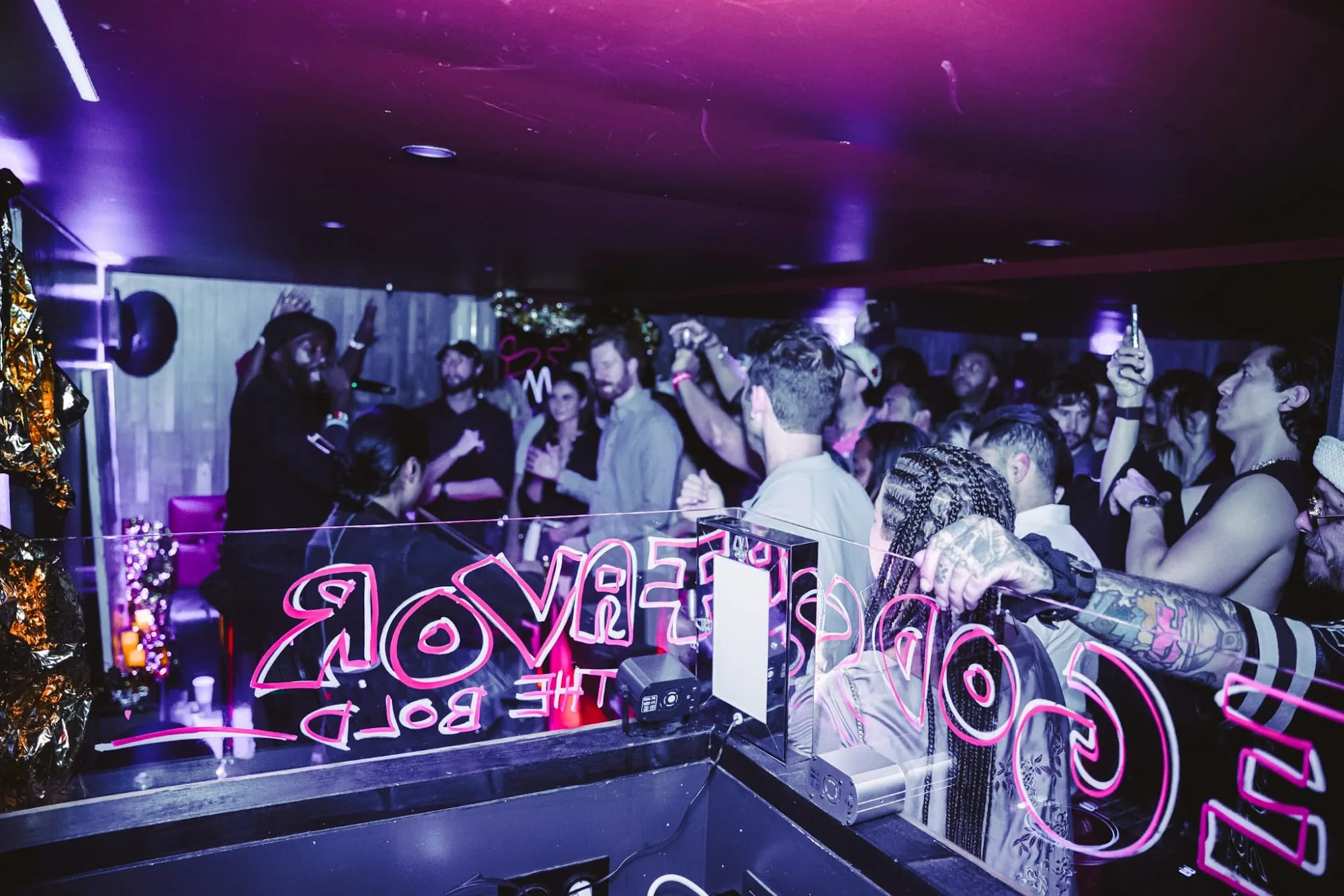 Interior party crowd with DJ neon sign at Balrog Bar, Cannes