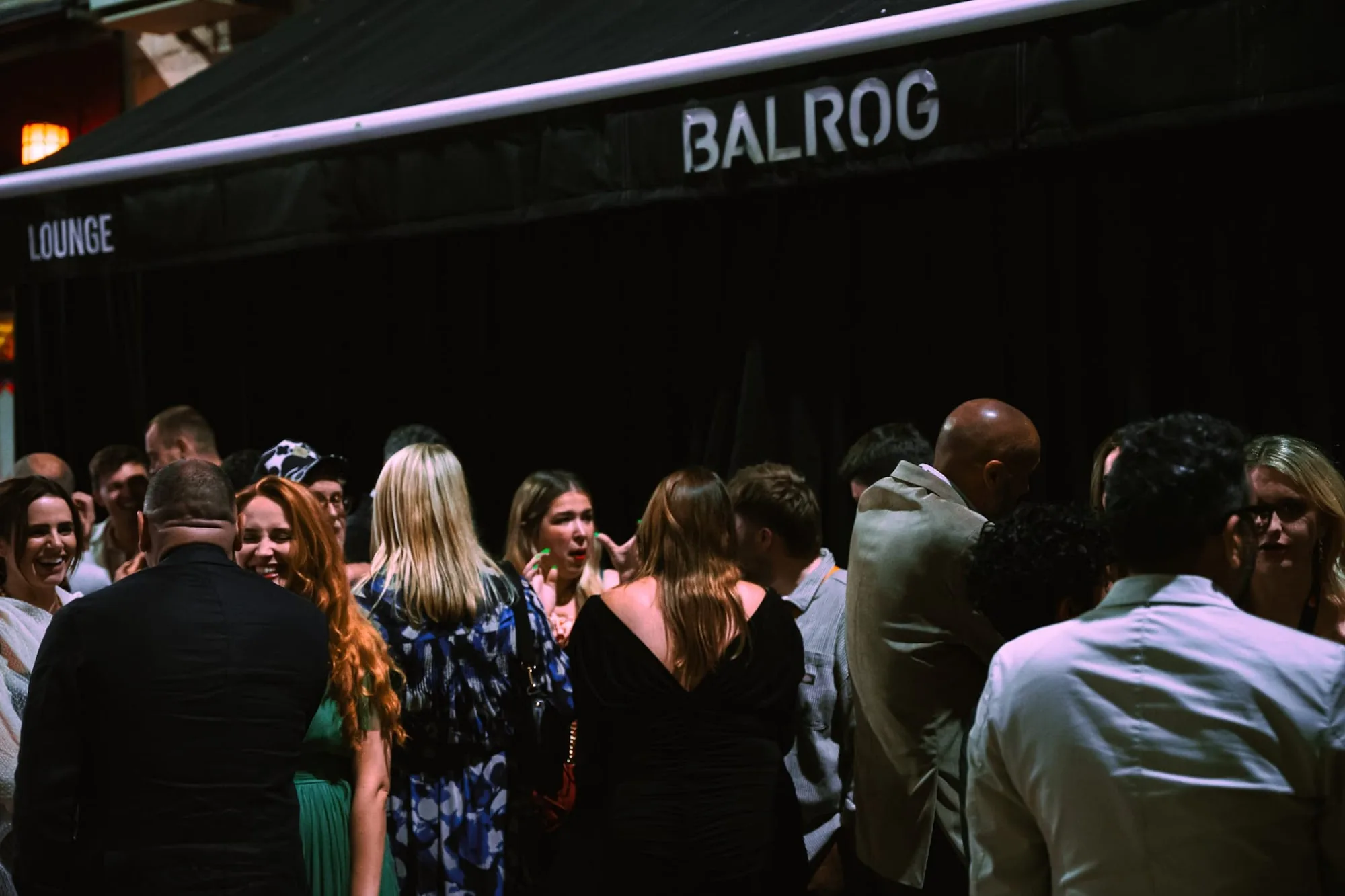 Large crowd outside Balrog Bar lounge with branded awning at night, Cannes