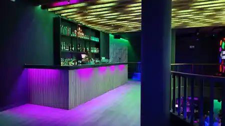 Bar with purple and green neon lighting and dance floor at Antilla Salsa, Barcelona