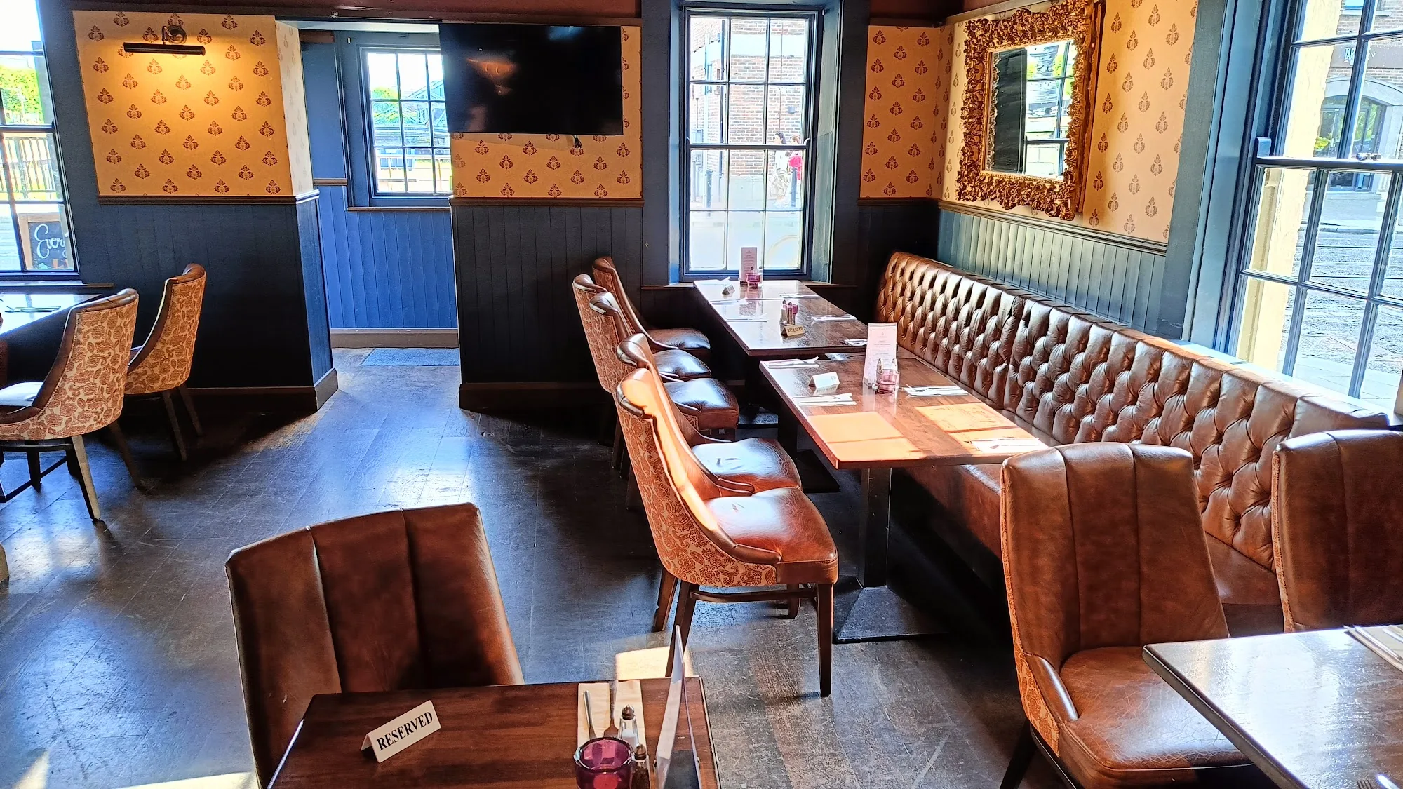 Cosy interior booth area at the Harbourmaster in Dublin with tan leather banquettes, patterned wallpaper and warm lighting