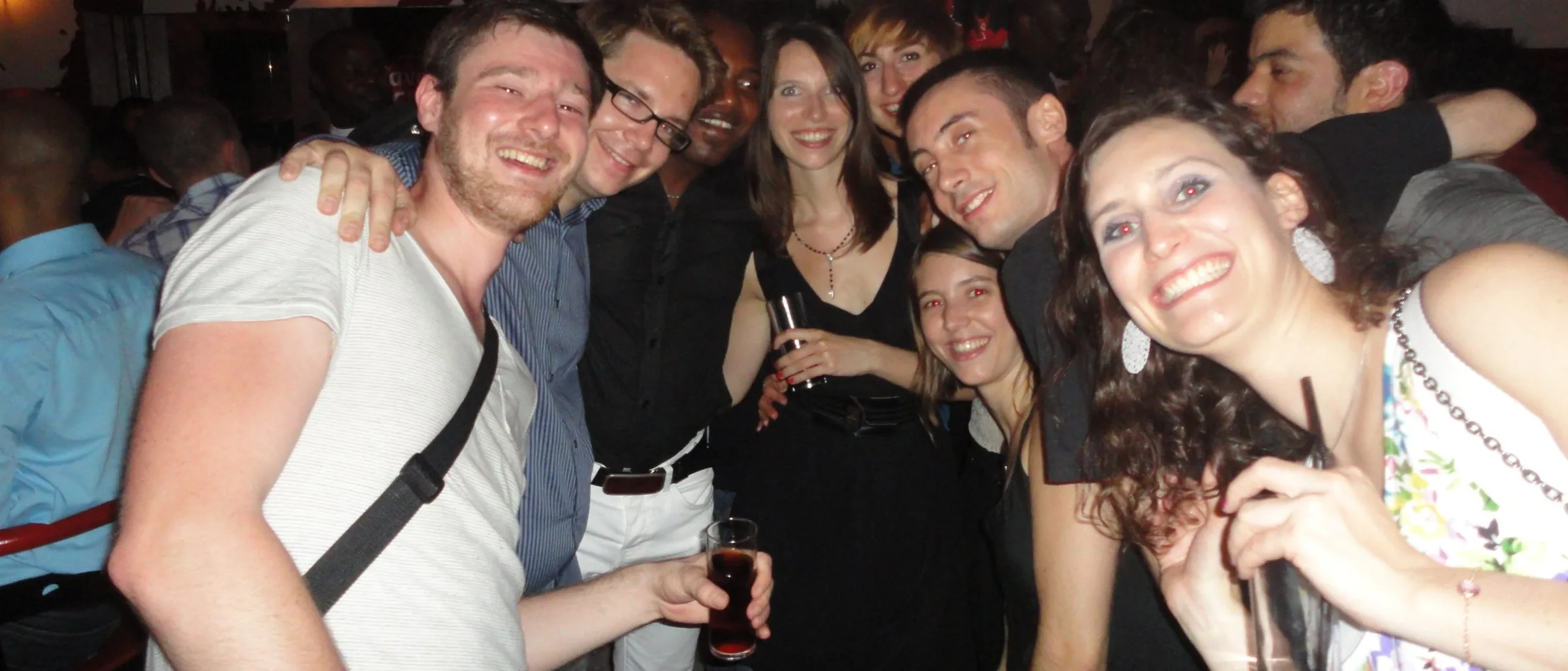 Group of smiling guests posing together with drinks during a party night at Cabana Cafe, Lyon.