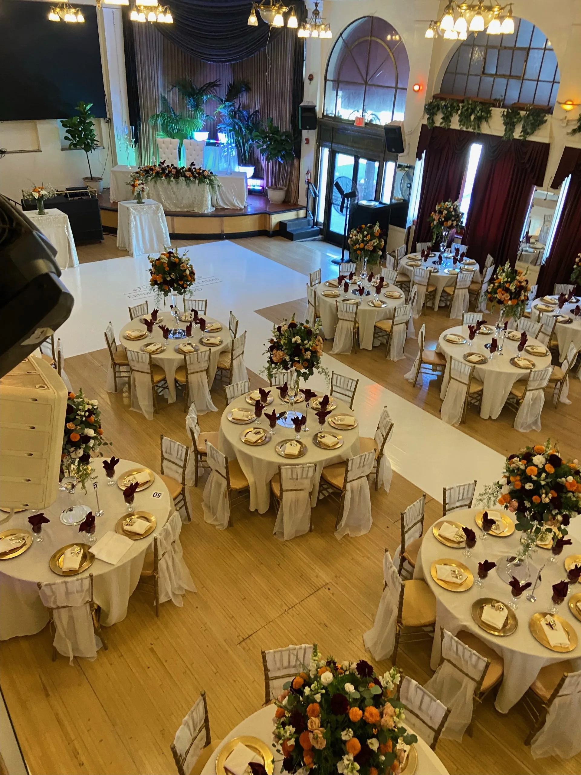 Interior ballroom set with round banquet tables, chandeliers and a stage beside the dance floor at The Granada LA, Los Angeles
