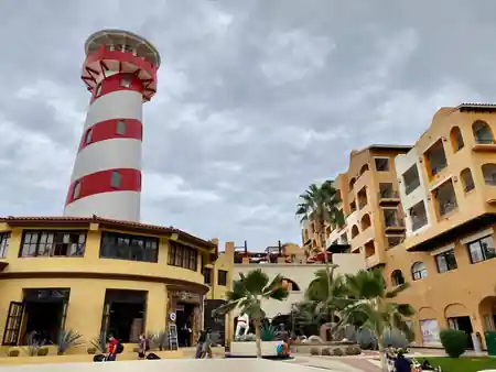 Red and white striped lighthouse tower at Tesoro Los Cabos resort with the venue buildings — salsa venue in Cabo San Lucas