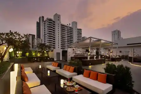 Rooftop bar at sunset with orange cushion seating at amBar Sheraton Bangkok — bachata venue in Bangkok