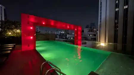 Rooftop pool and bar with red and green neon lighting at amBar Sheraton Bangkok — bachata venue in Bangkok