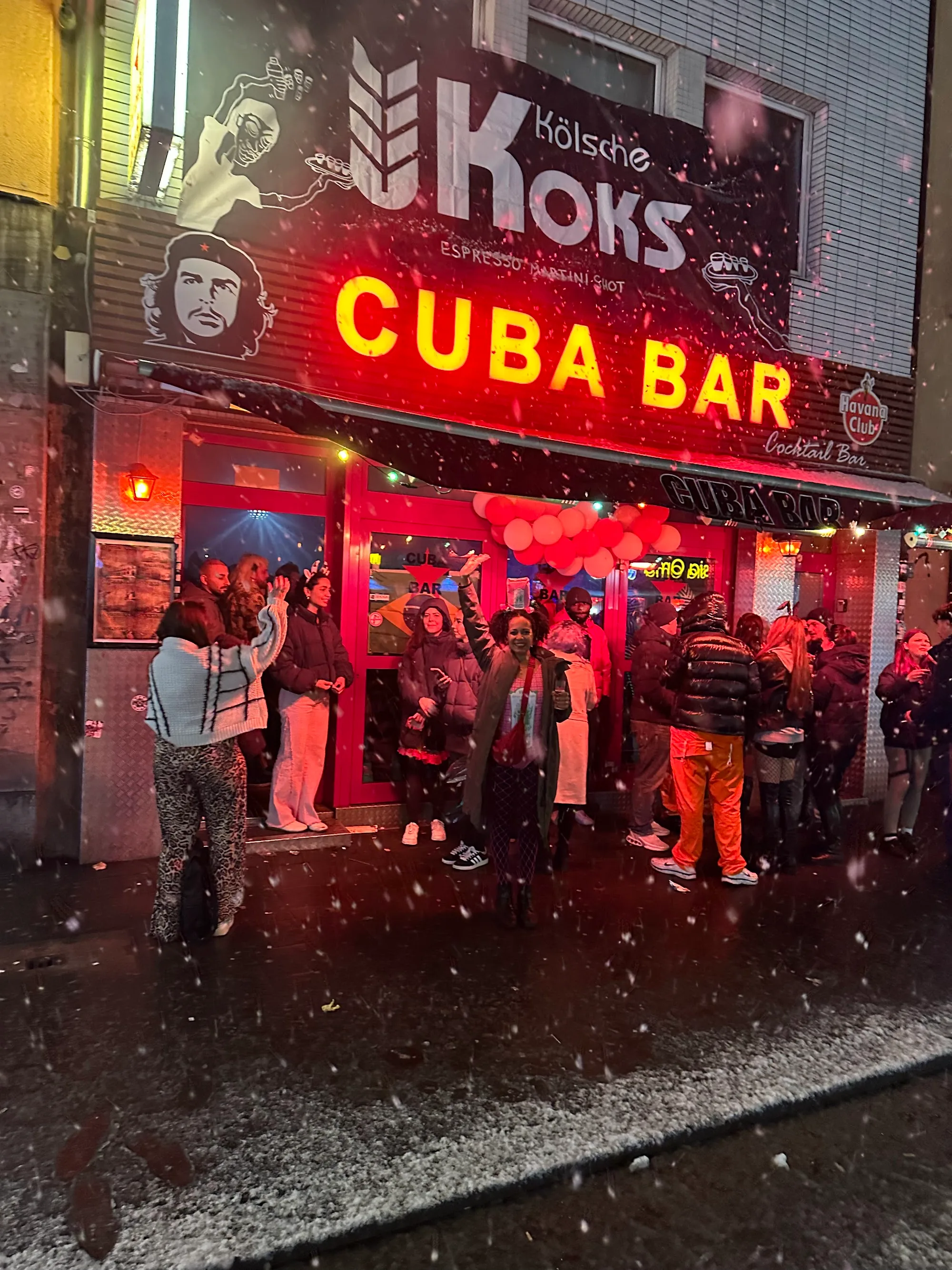 Cuba Bar neon sign entrance with crowd outside in snowy Cologne night