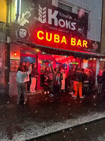 Cuba Bar neon sign entrance with crowd outside in snowy Cologne night — salsa, bachata venue in Cologne