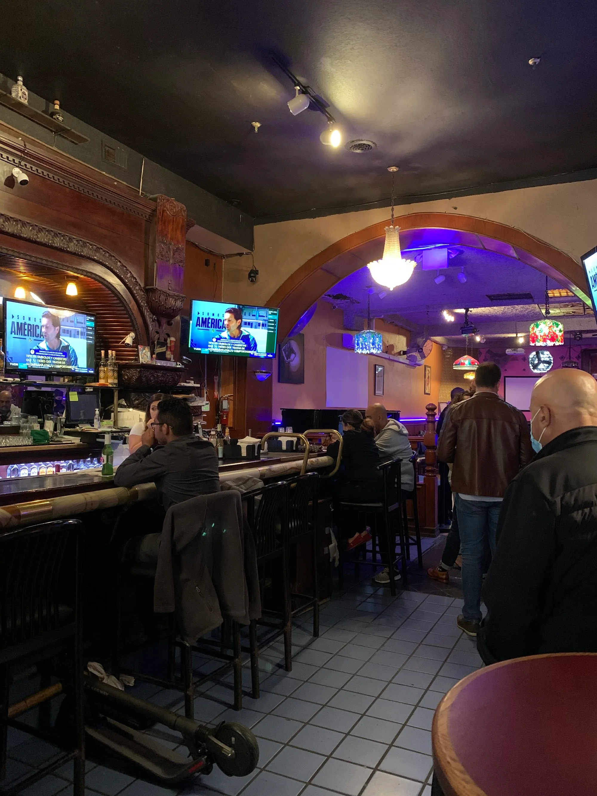 Bar interior with patrons under blue lighting at El Valenciano in San Francisco