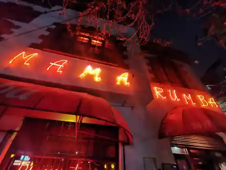 Mama Rumba neon sign glowing at the venue entrance in Madrid Spain at night — bachata, salsa venue in Mexico City