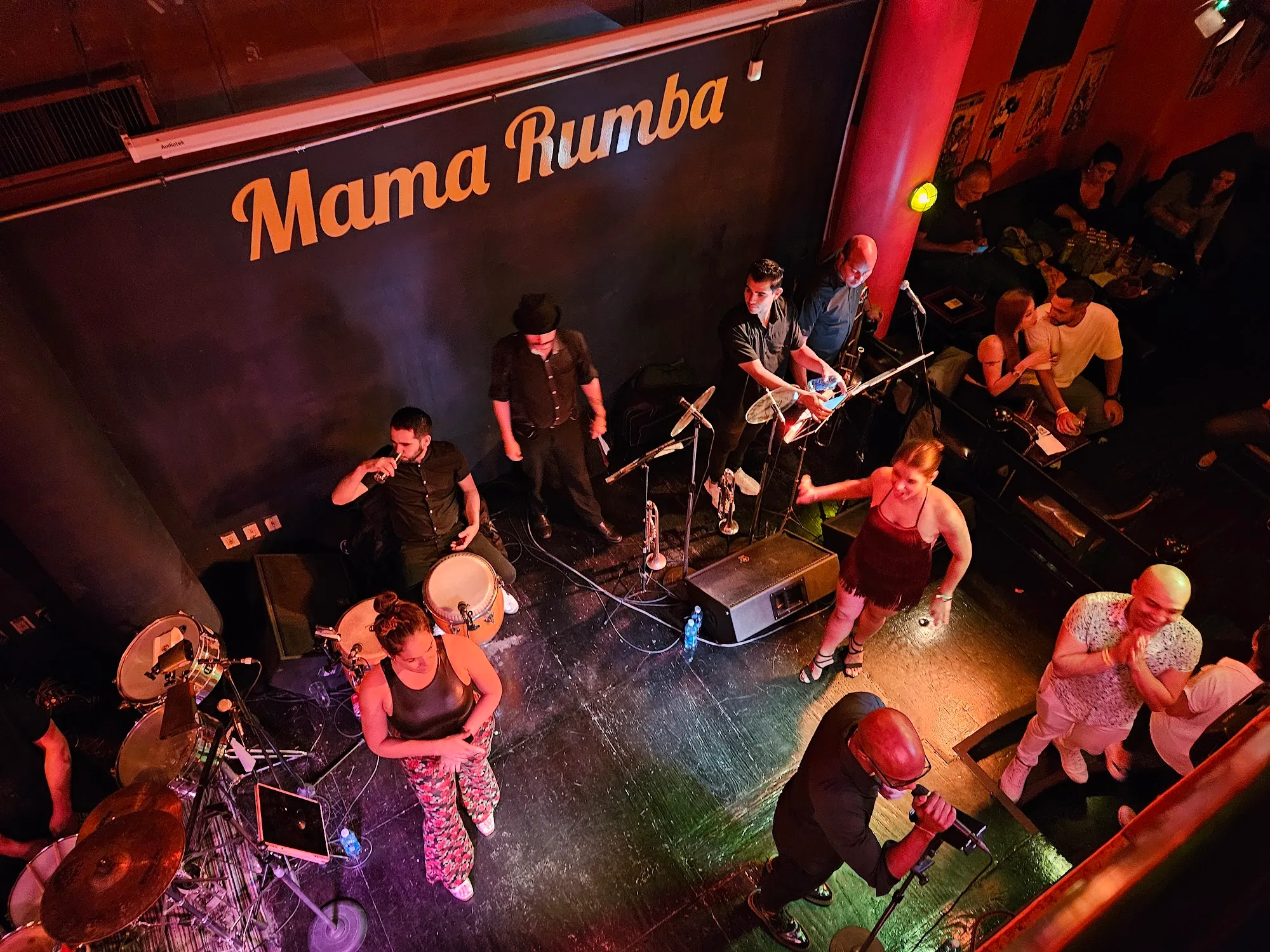 Bird's eye view of live band performing at Mama Rumba with crowd and venue sign in Madrid