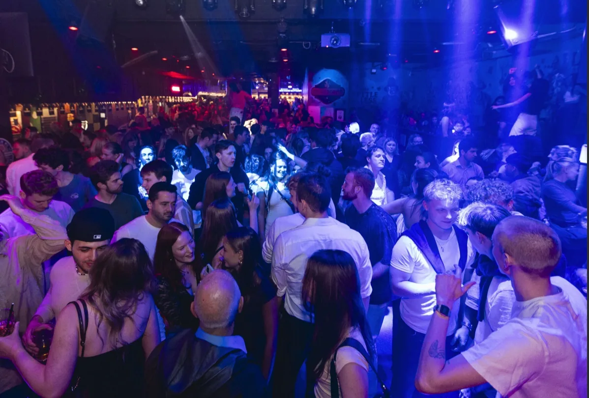 Packed dance floor and crowd inside a Copenhagen nightspot under blue and red party lighting
