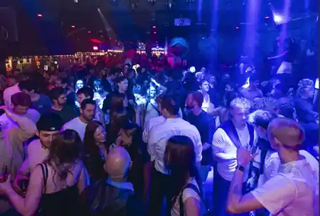 Packed dance floor and crowd inside a Copenhagen nightspot under blue and red party lighting, salsa, bachata venue in Copenhagen