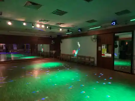 Green-lit dance studio with mirrors and stage lighting at Tanzschule Wilfego in Nuremberg — salsa, bachata, kizomba venue in Nuremberg