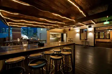Upstairs rooftop bar interior with warm string lights and timber ceiling at Pyrmont Bridge Hotel, Sydney — bachata venue in Sydney