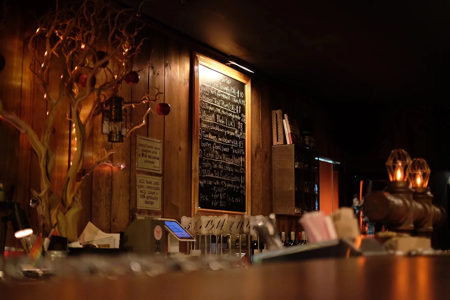 Warmly lit bar interior with chalkboard menu and wood paneling at Upcider San Francisco