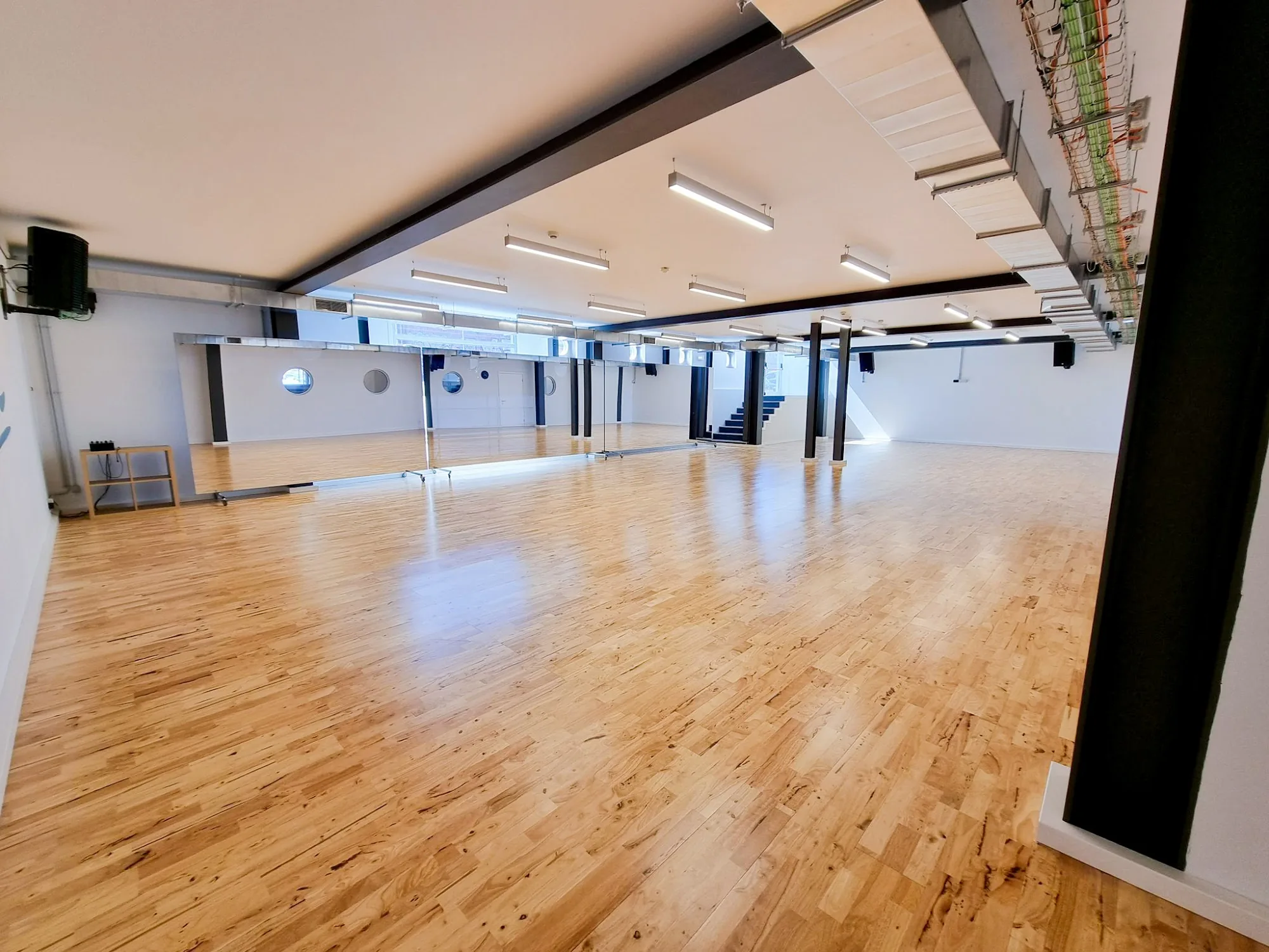 Bright dance studio with wooden floor and mirrors at UDance School Lisbon