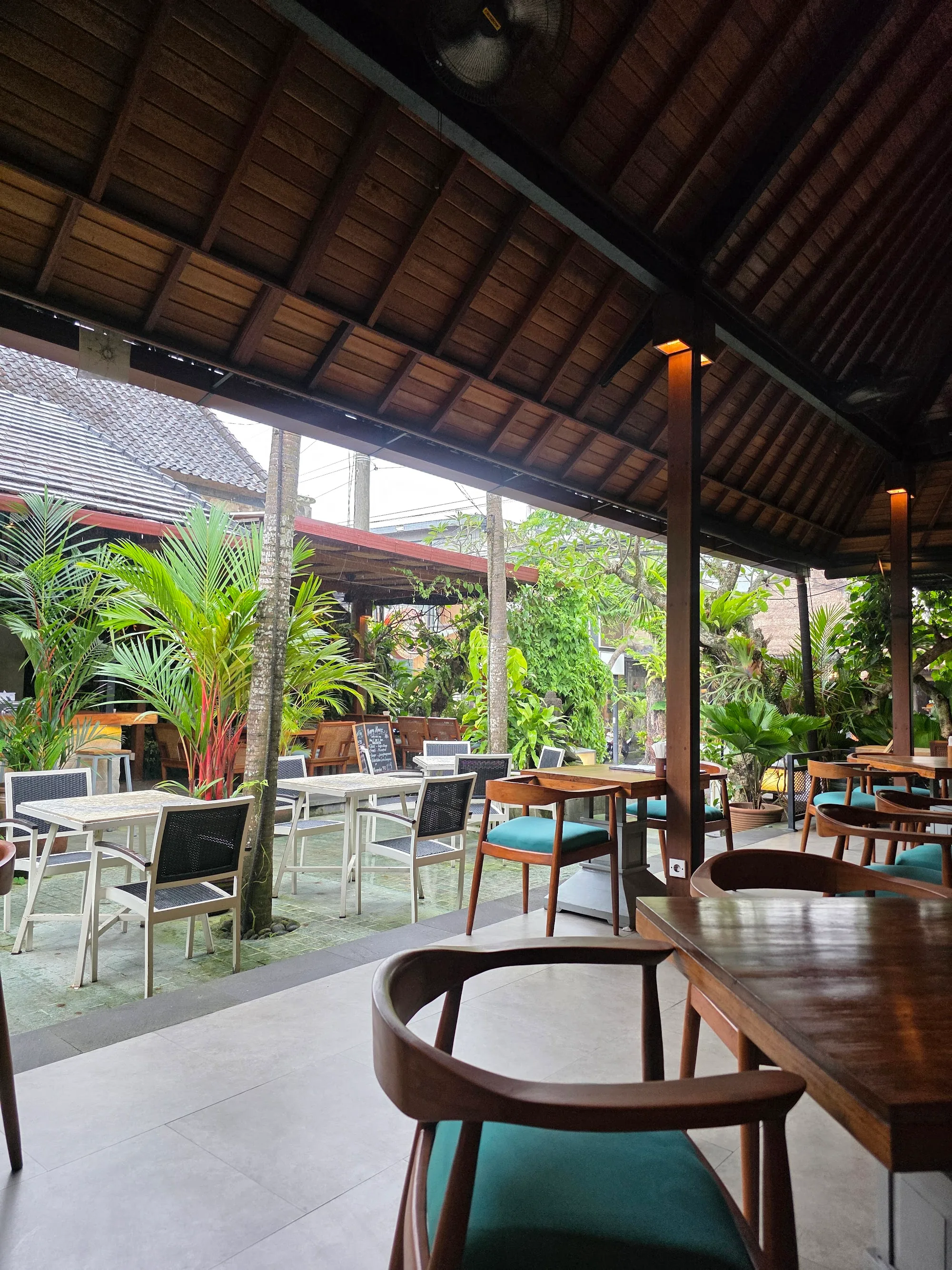 Open-air interior of Laughing Buddha Bar in Bali with tropical plants and lounge seating