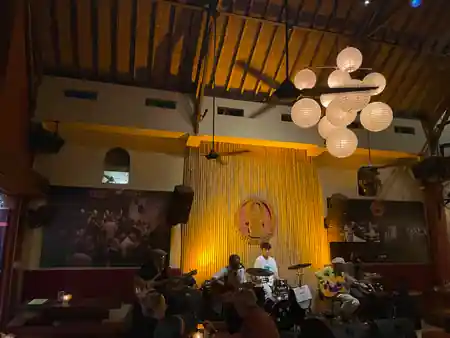 Live band performing on stage at Laughing Buddha Bar in Bali under bamboo backdrop and pendant lights — salsa, bachata venue in Bali
