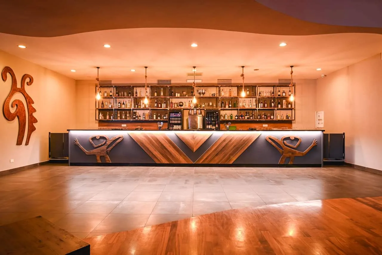 Backlit bar with dancer carvings and wooden dance floor at Salsa Nightclub in Rome