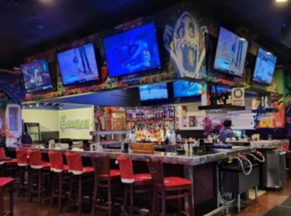 Colorful graffiti-wall bar with TV screens and red stools at Rai's Rendezvous, Ashburn