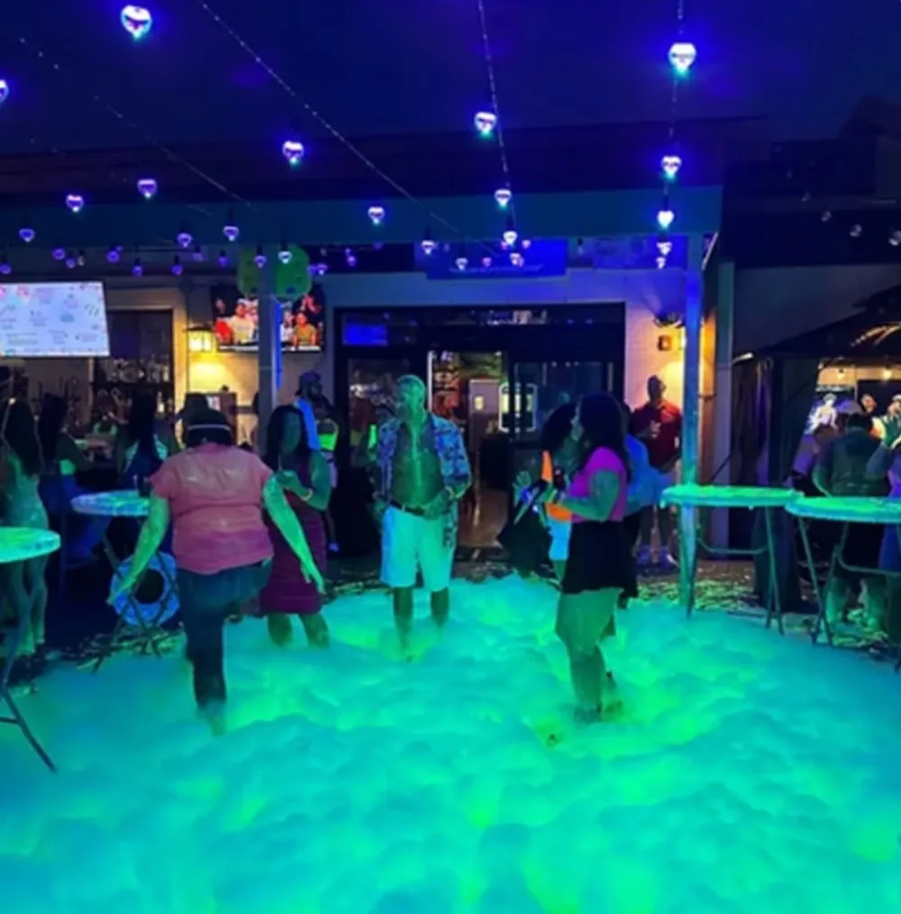 Nighttime foam party crowd under lights on the patio at Rai's Rendezvous, Ashburn