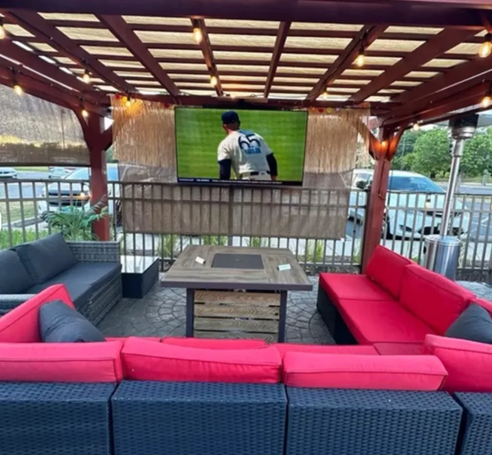 Covered patio cabana with red lounge couches and big screen at Rai's Rendezvous, Ashburn