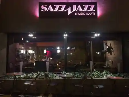 Illuminated Sazz Jazz music room signage above the entrance of The Embassy Room Brussels at night, kizomba venue in Brussels