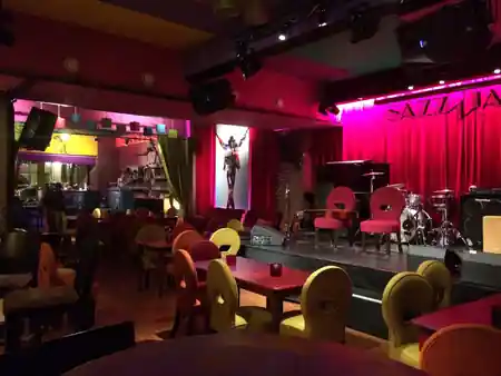 Pink-lit stage with drum kit and colorful seating in the main music room at The Embassy Room Brussels, kizomba venue in Brussels