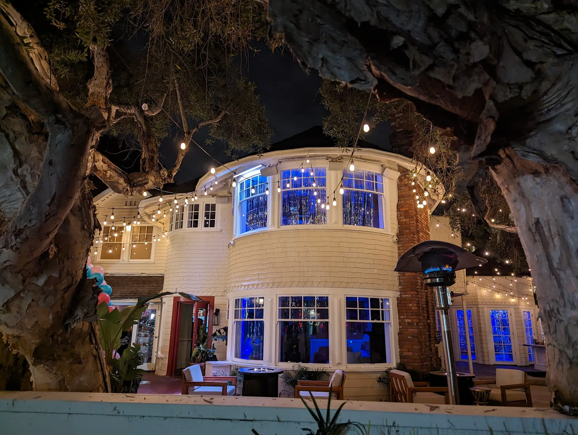 Night exterior of The Victorian tower building with festival lights and crowd in LA
