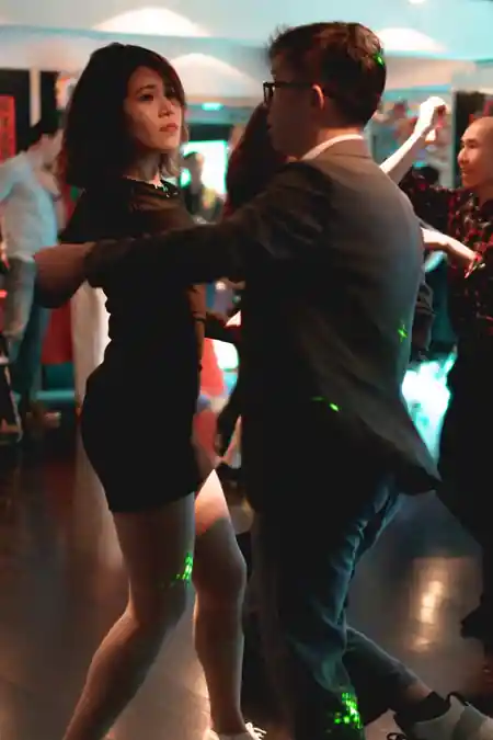 Couple dancing salsa at a social night at 8th Floor Fung Woo Centre in Hong Kong, with colorful party lighting creating a vibrant atmosphere on the dance floor