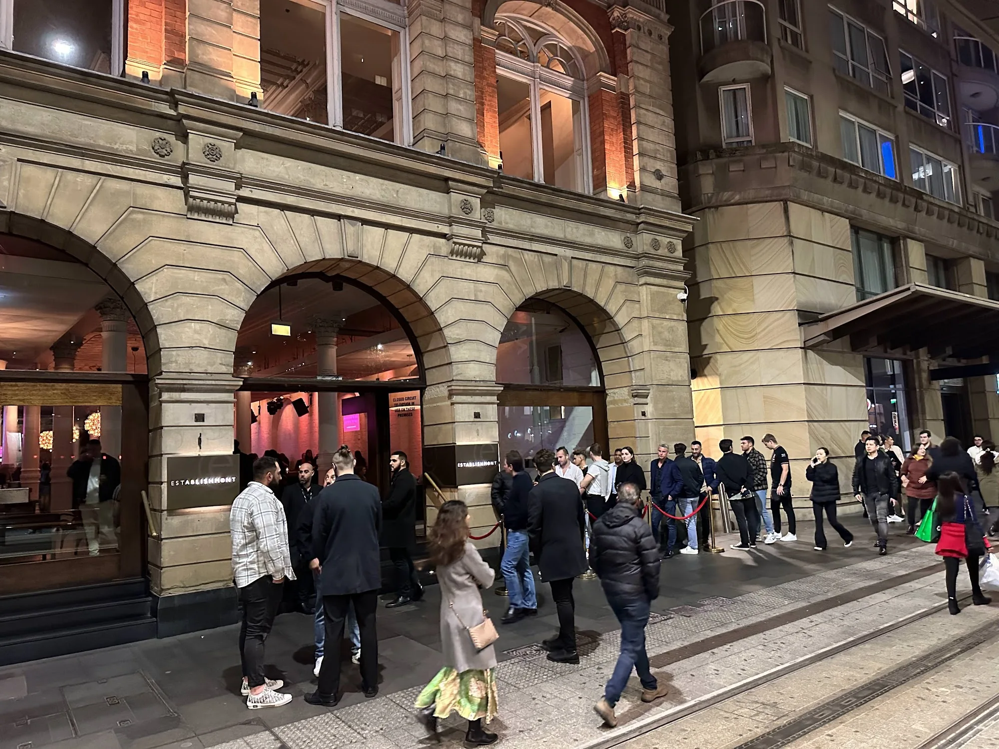 Evening crowd queues at the arched entrance of Establishment Bar Sydney for a Saturday night out