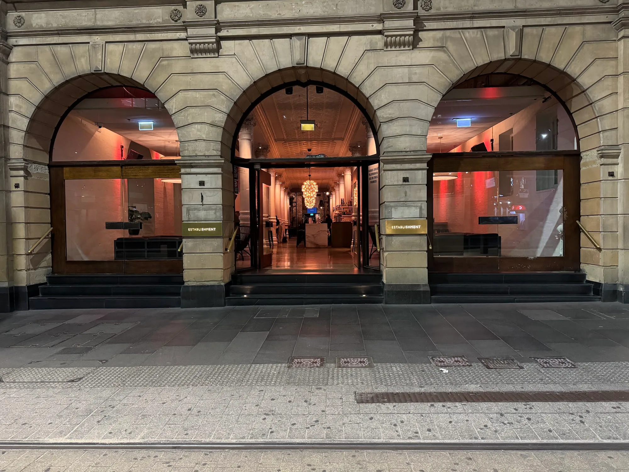 Triple sandstone arches mark the illuminated Establishment Bar entrance in Sydney CBD at night