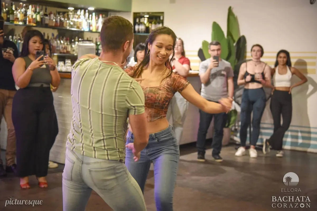 Bachata dancers mid-turn at The Space Dance & Arts Centre Melbourne with crowd and bar visible