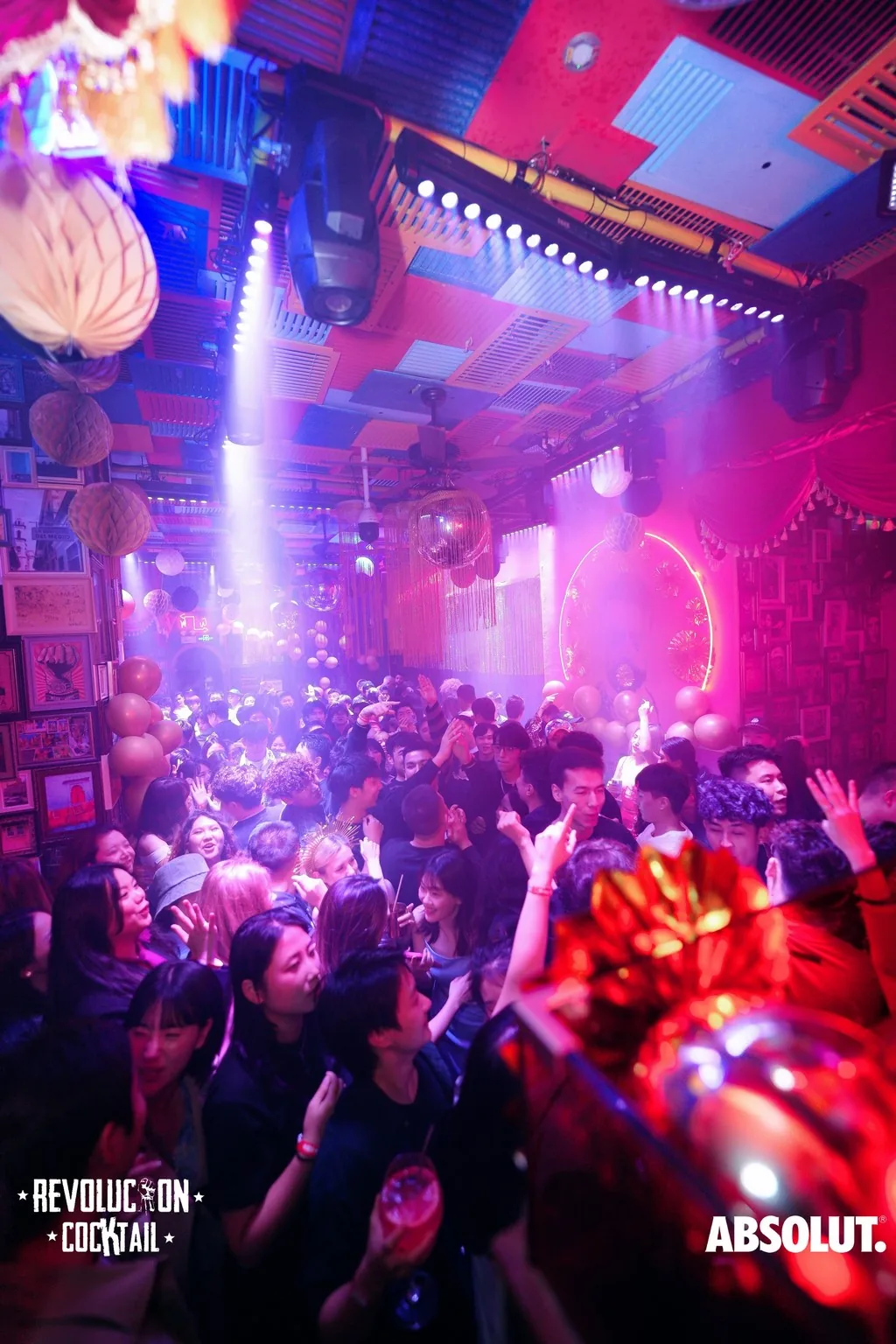 Packed crowd under colorful club lights at Revolucion Cocktail, Shenzhen — salsa, bachata venue in Shenzhen