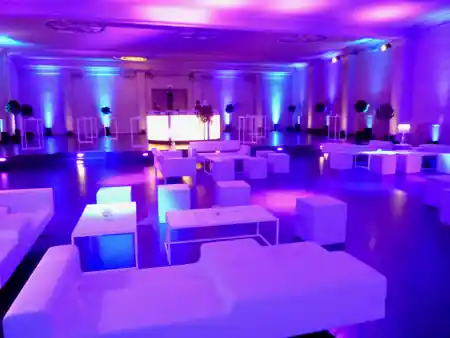 Purple and blue club lighting over white lounge seating and a lit bar in the main hall of Albert Hall Brussels set up for a party, bachata venue in Brussels