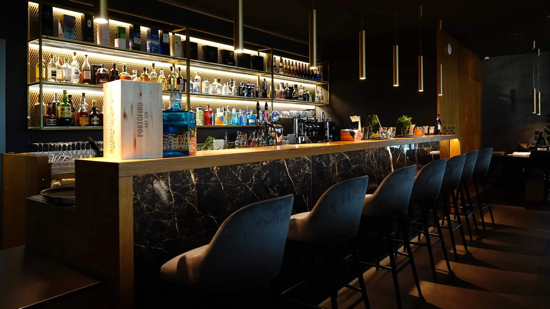Stylish lounge bar at Terrazza 13 with backlit shelves and pendant lighting in Milan