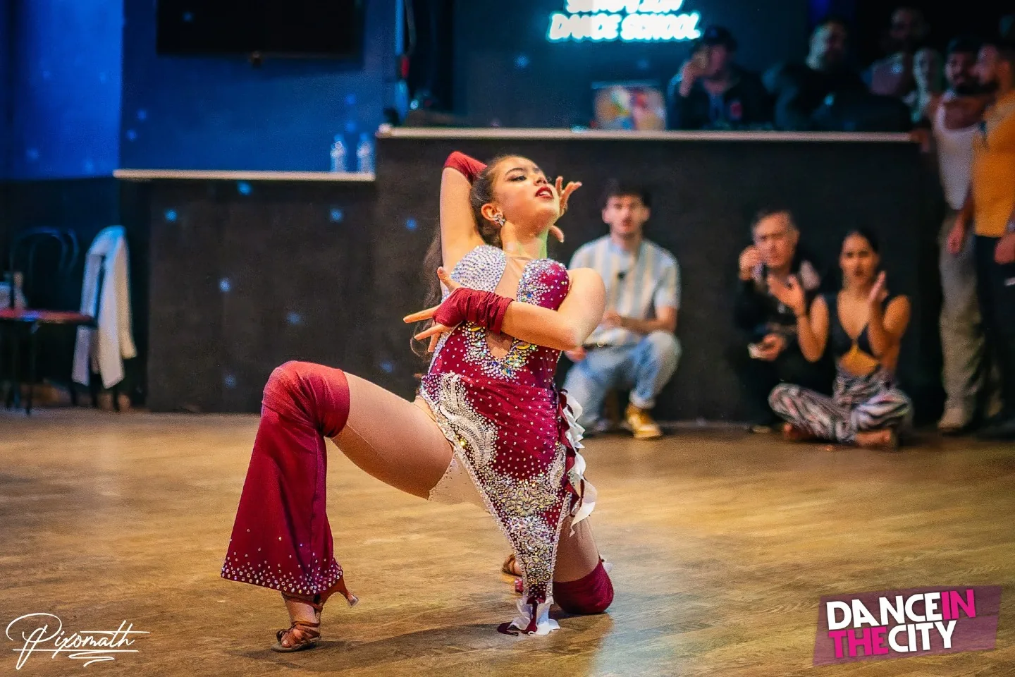 Salsa performer in red costume on the wooden dance floor at Dance In The City venue in Paris